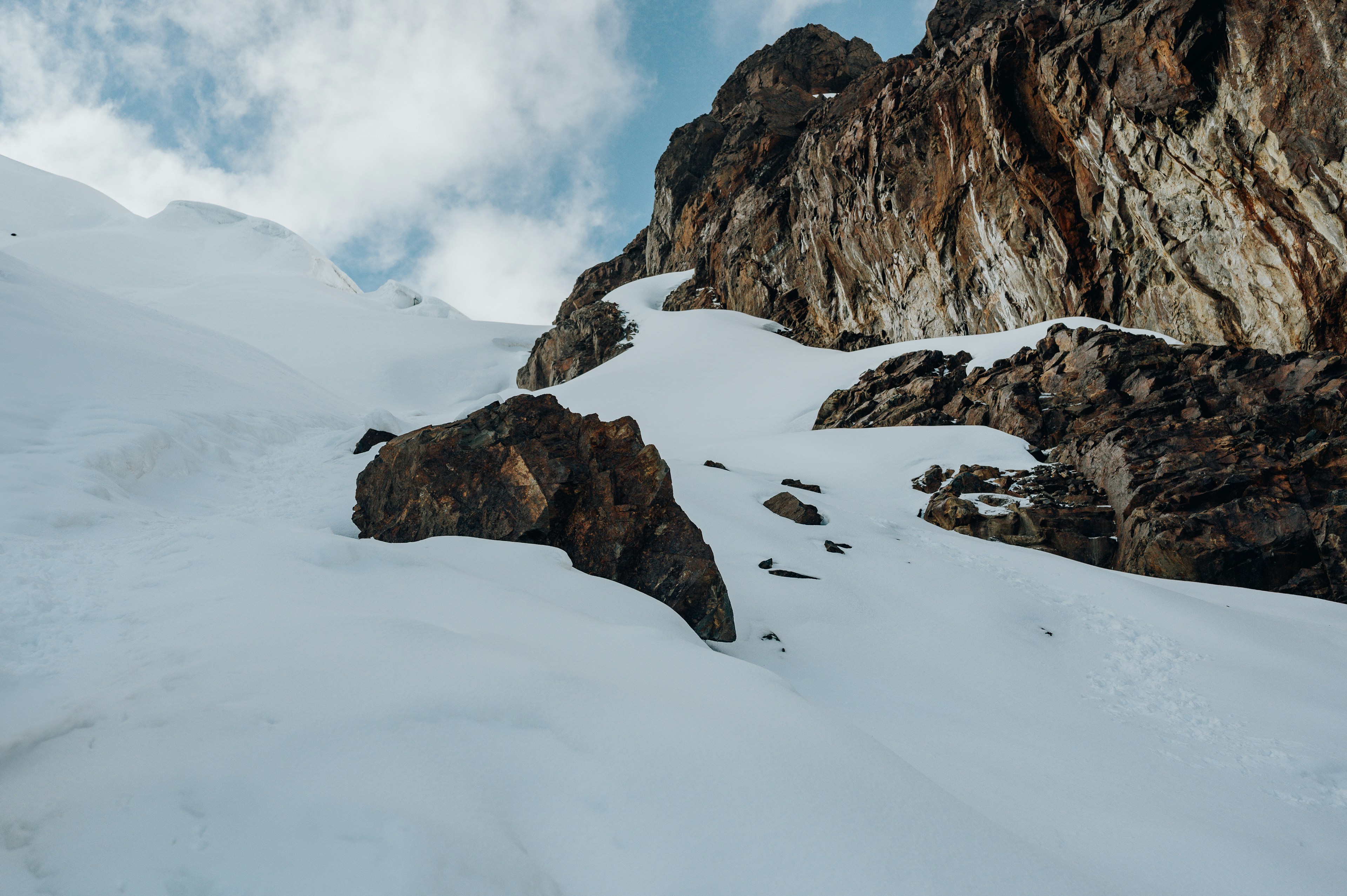 Verschneite Berge und Felswände unter einem wolkenverhangenen Himmel.