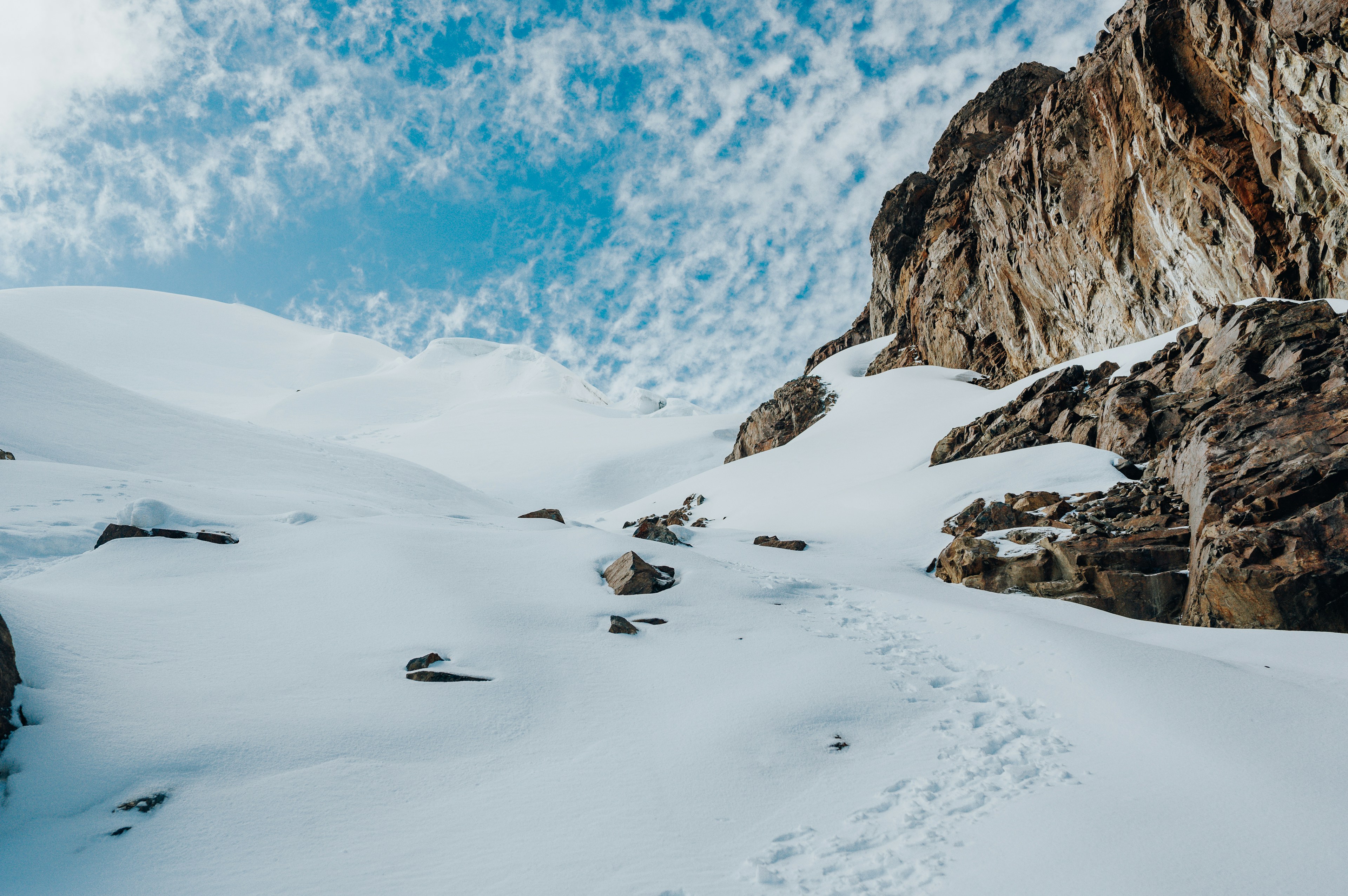 Schneebedeckter Berg mit blauem Himmel und Wolken.
