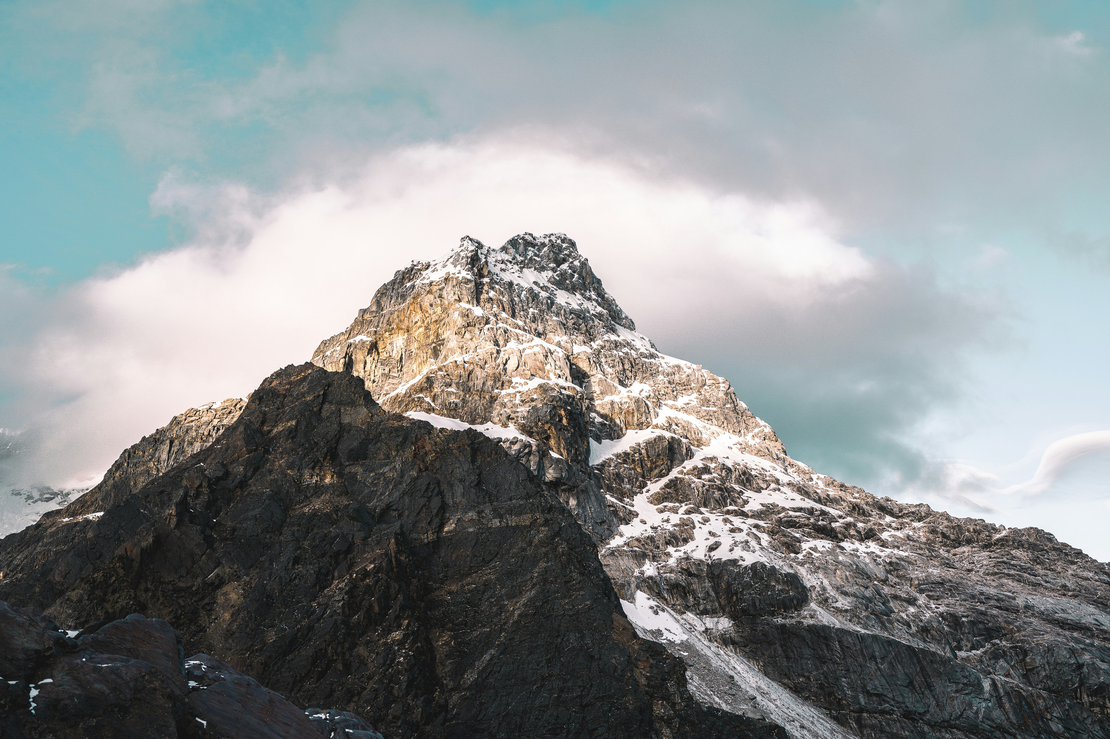 Ein majestätischer Berggipfel unter einem wolkenverhangenen Himmel.