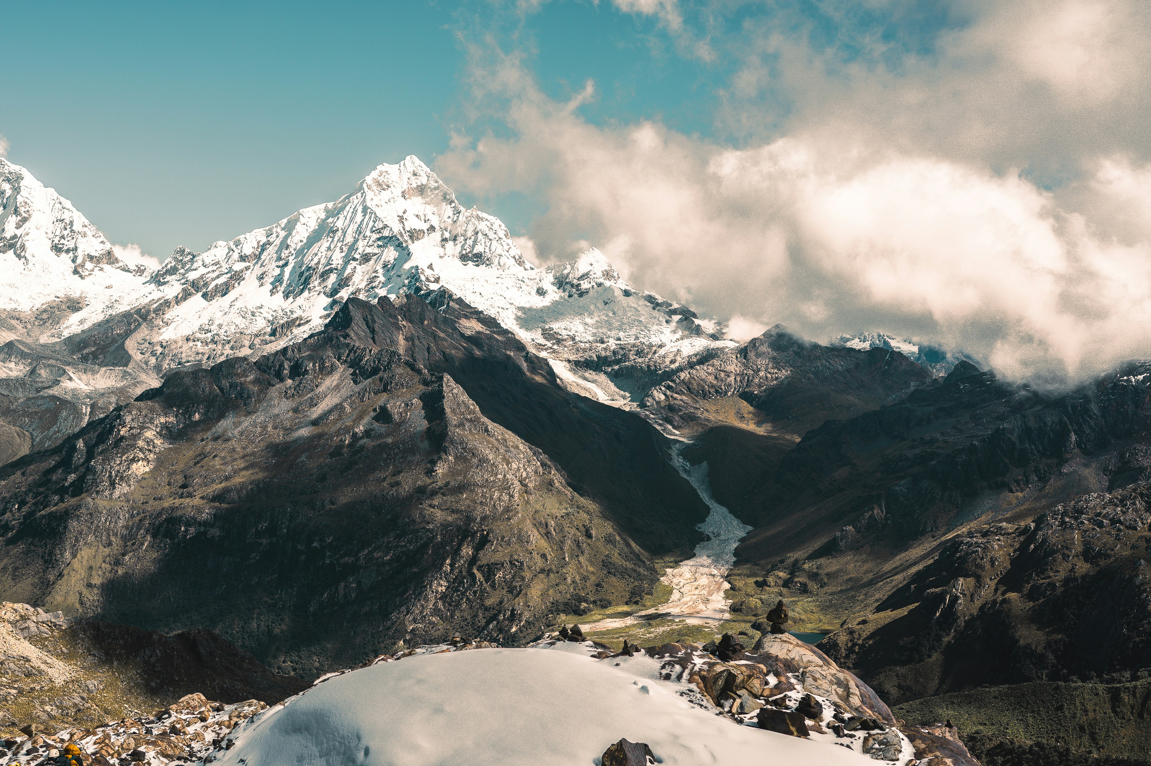 Verschneite Berge ragen unter einem teilweise bewölkten Himmel empor.
