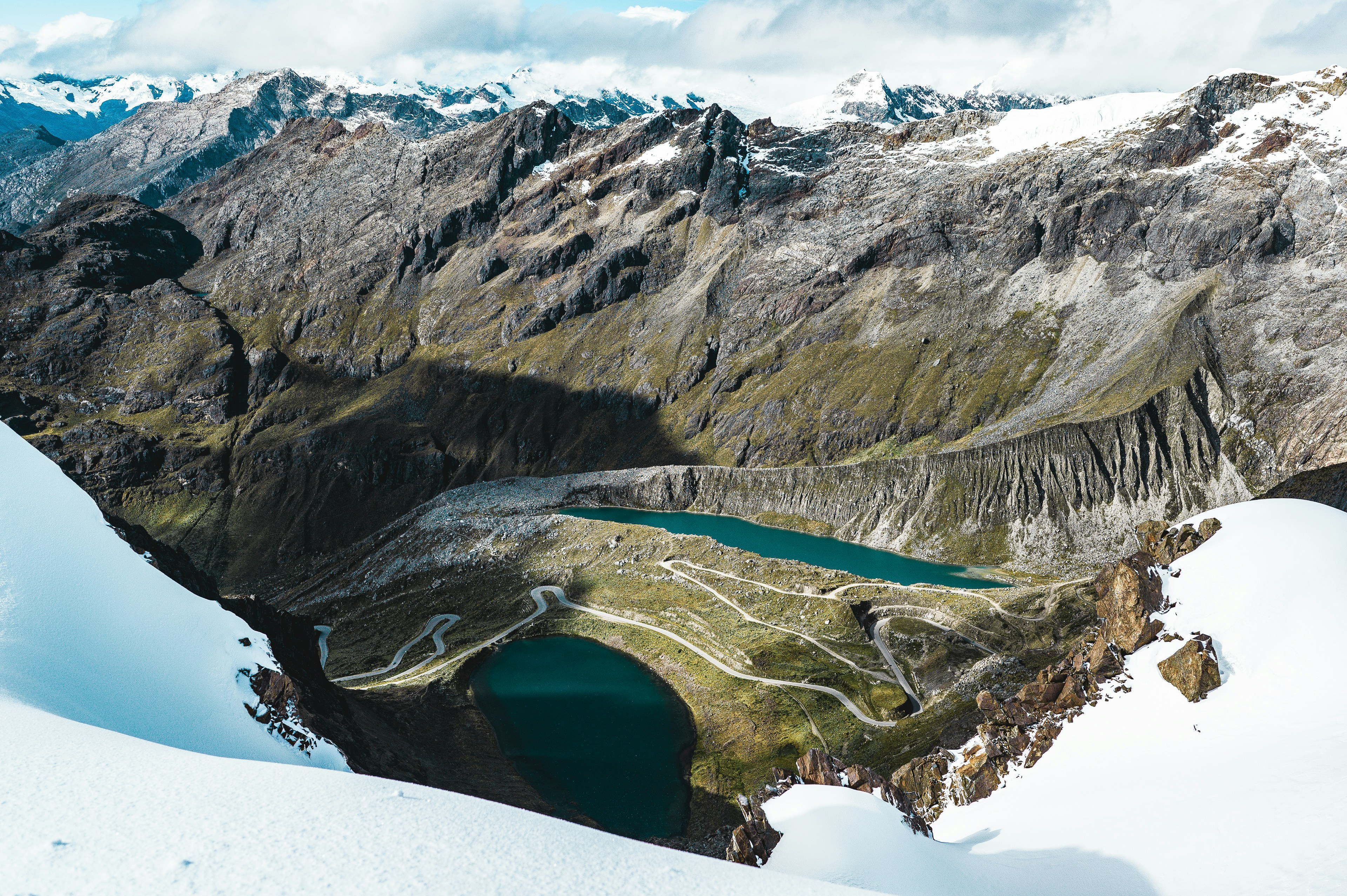 Verschneite Berge mit zwei tiefblauen Seen.