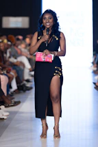 A woman speaks into a microphone at a fashion show.