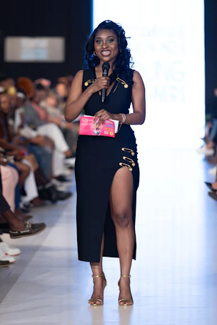 A woman speaks into a microphone at a fashion show.