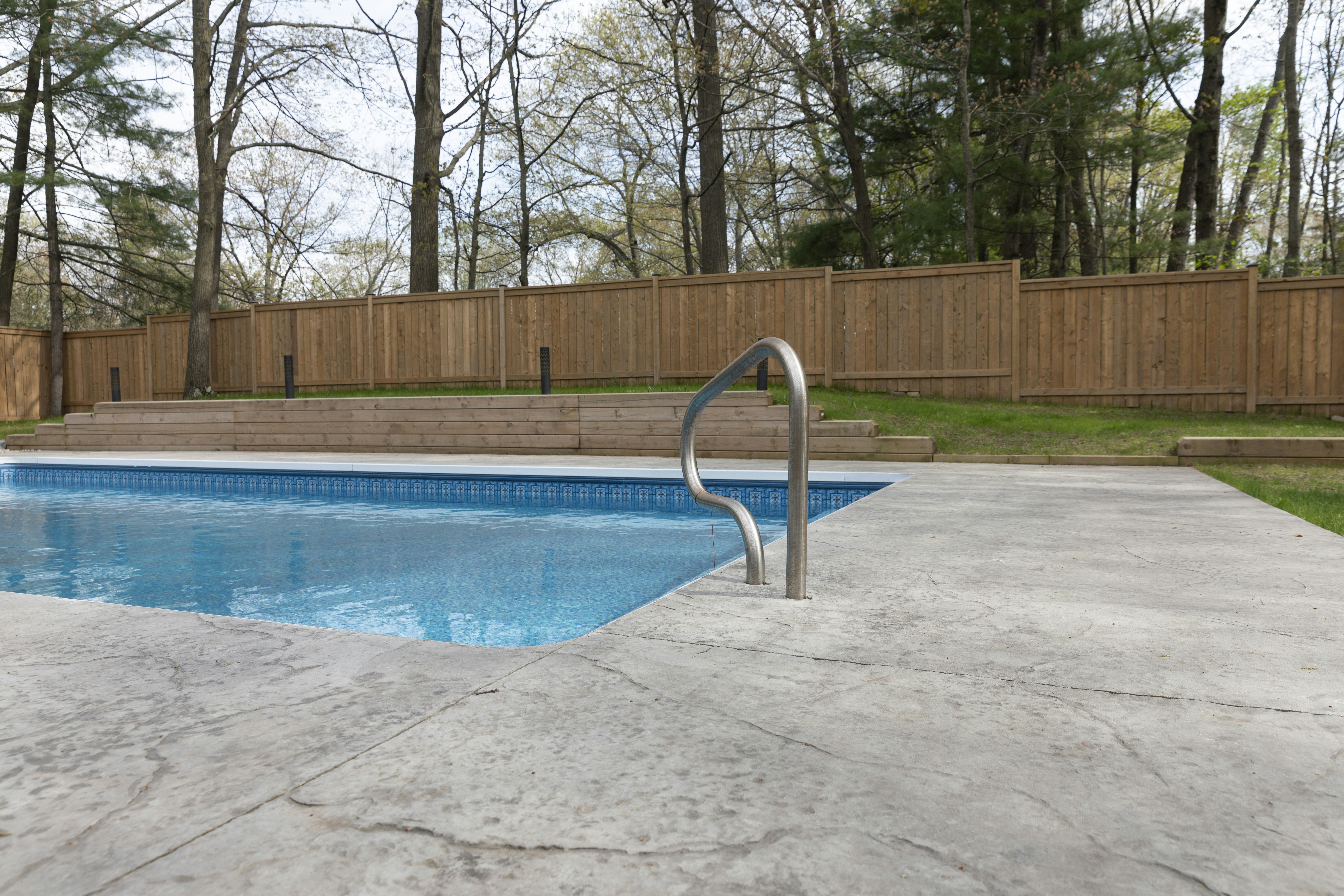A pool is near a wooden fence.