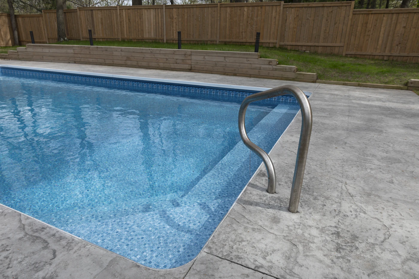 Backyard fiberglass-style swimming pool with clear water and patio