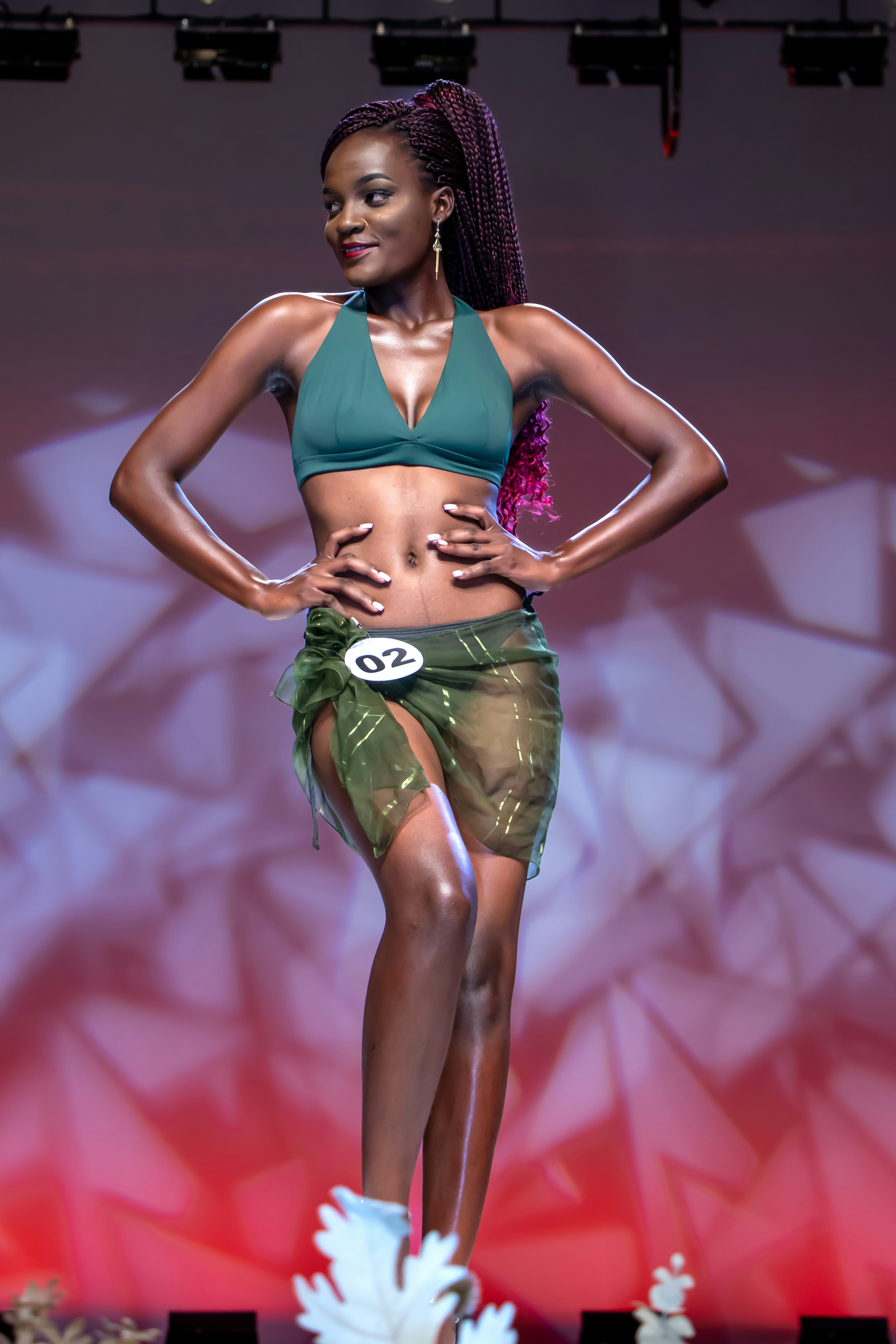 A woman confidently poses on stage in a bikini.