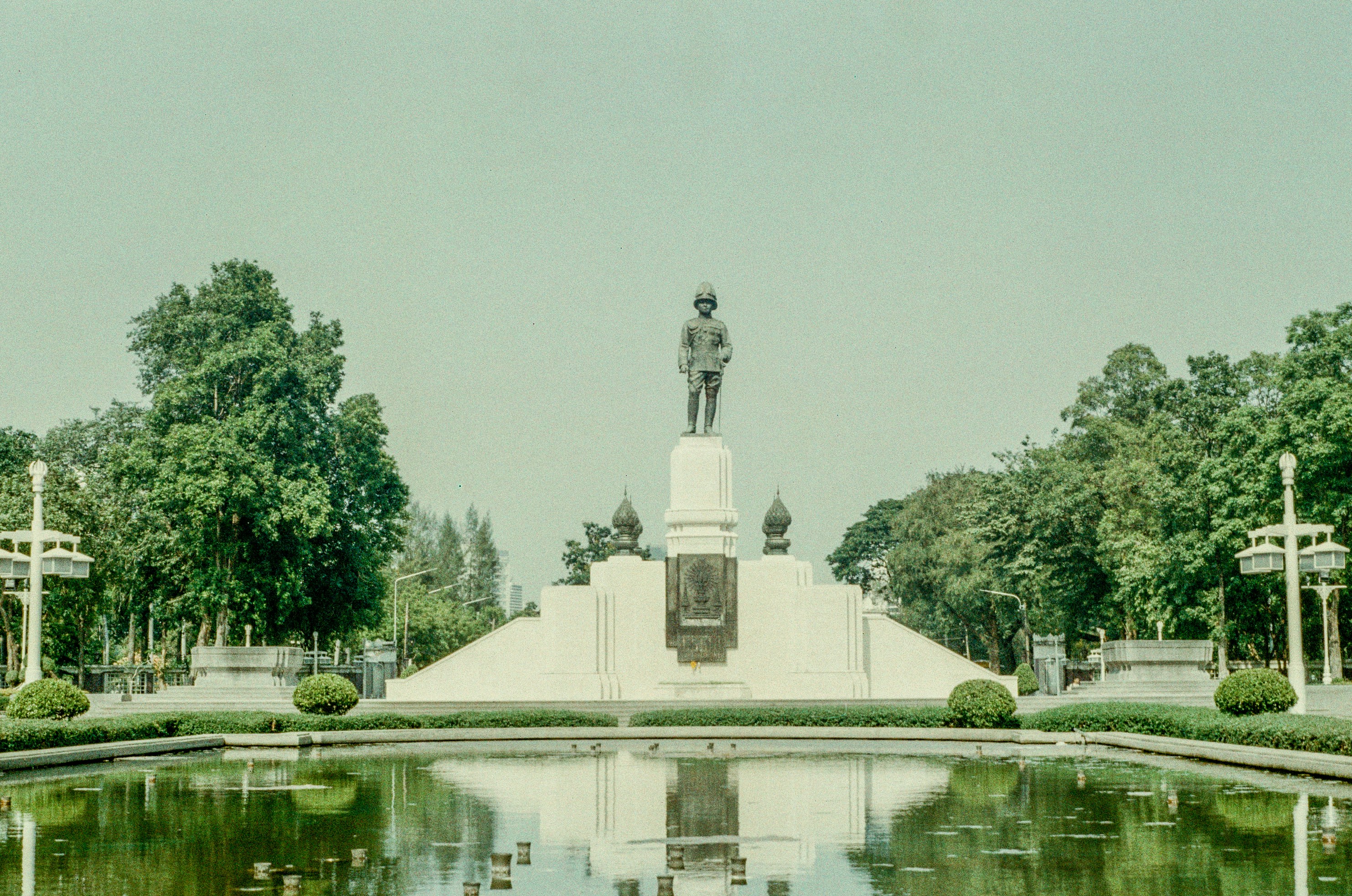 A statue stands over a reflecting pool.