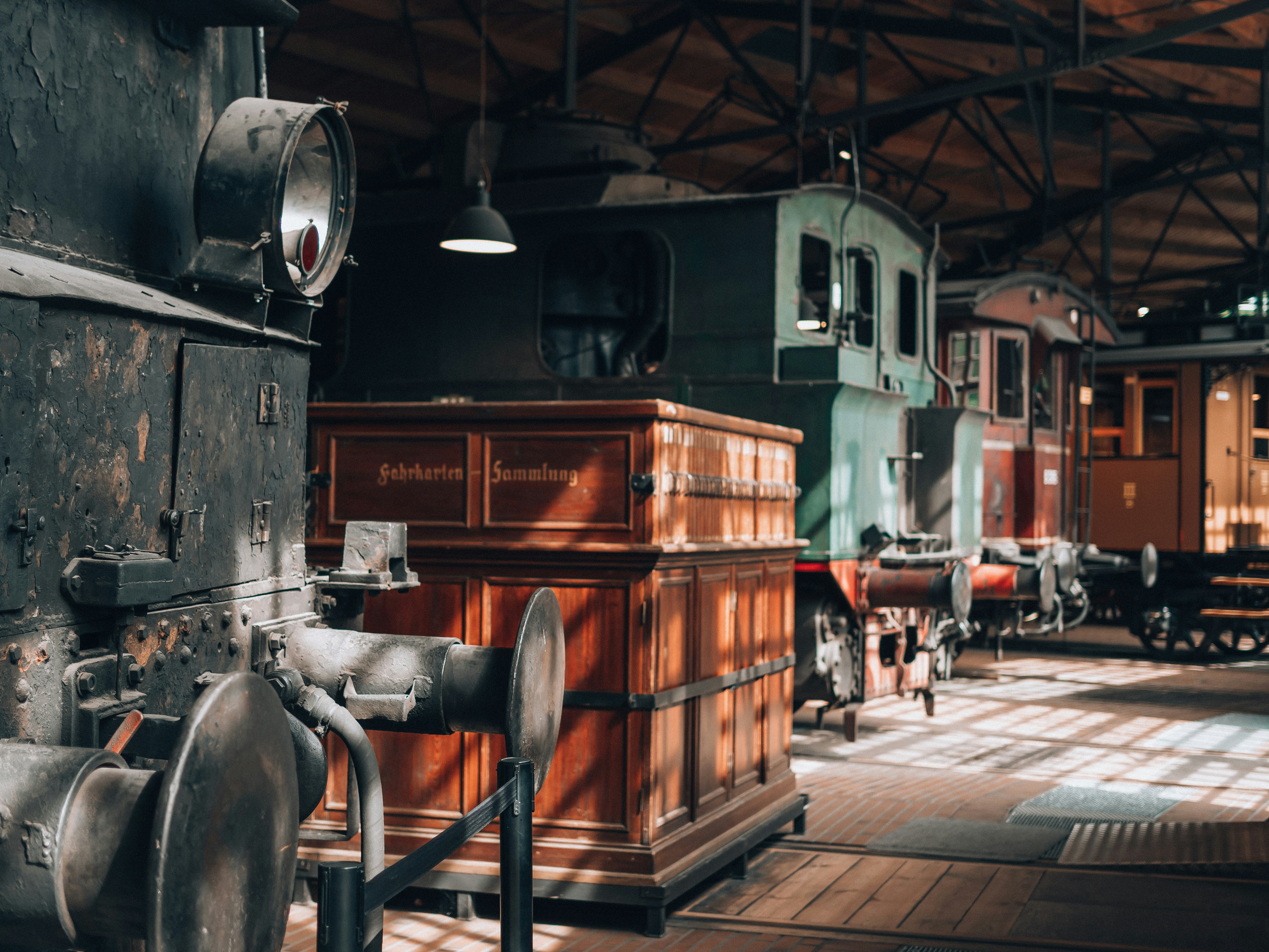 Old trains sit inside a dim train depot