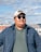 A man wearing sunglasses looks away from the camera.