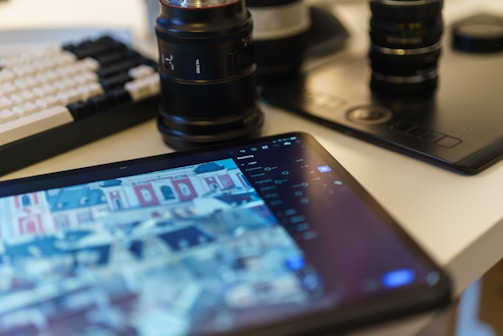 Tablet, keyboard, and camera lenses are on a desk.