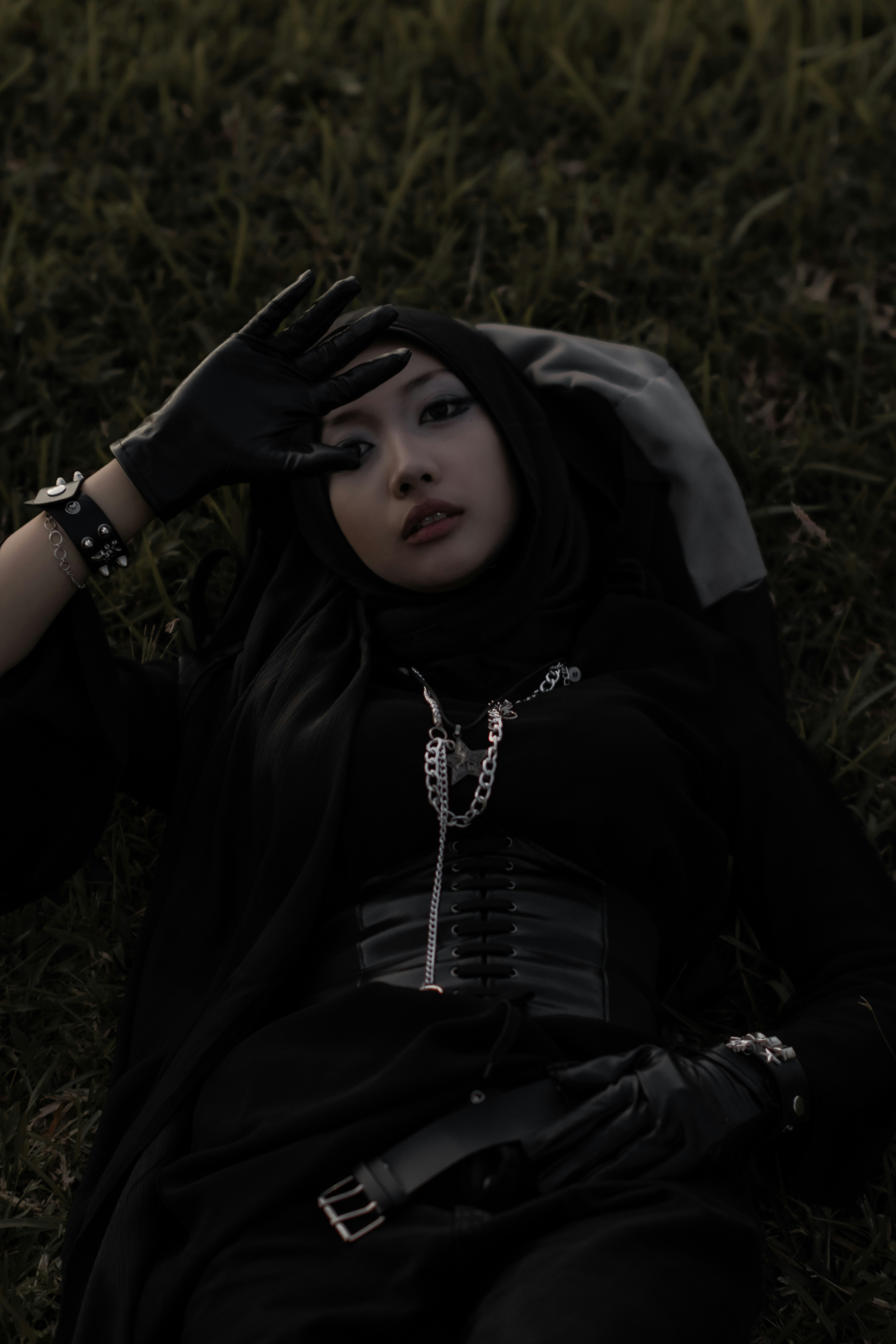 Seorang wanita berpakaian hitam beristirahat di rerumputan.