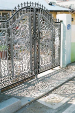 Ornate wrought-iron gates cast shadows on the pavement.