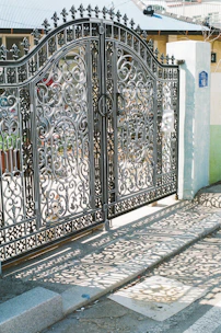 Ornate wrought-iron gates cast shadows on the pavement.