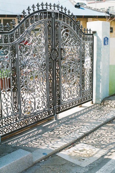 Ornate wrought-iron gates cast shadows on the pavement.