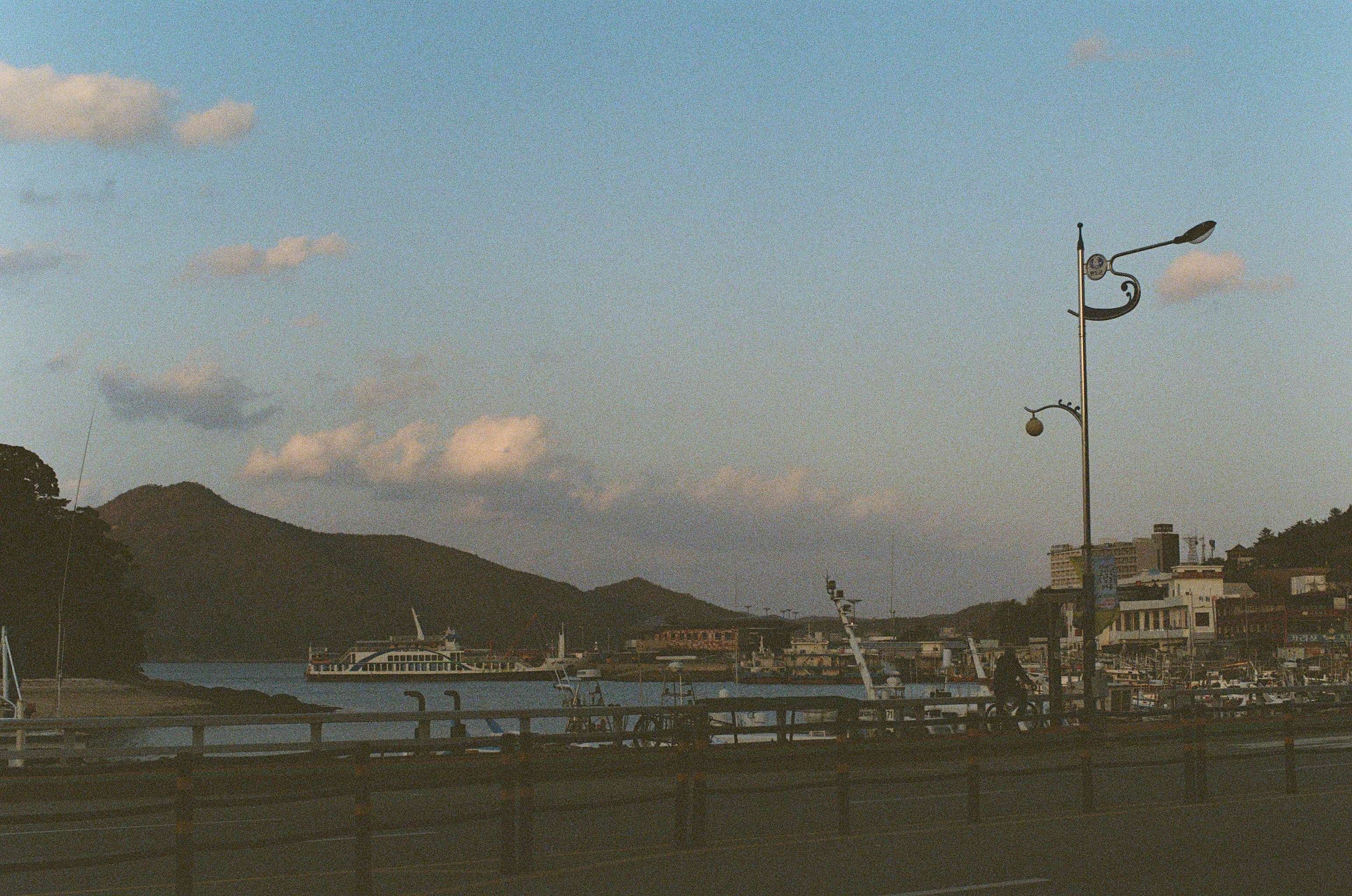 Harbor scene with ships, mountains, and buildings.
