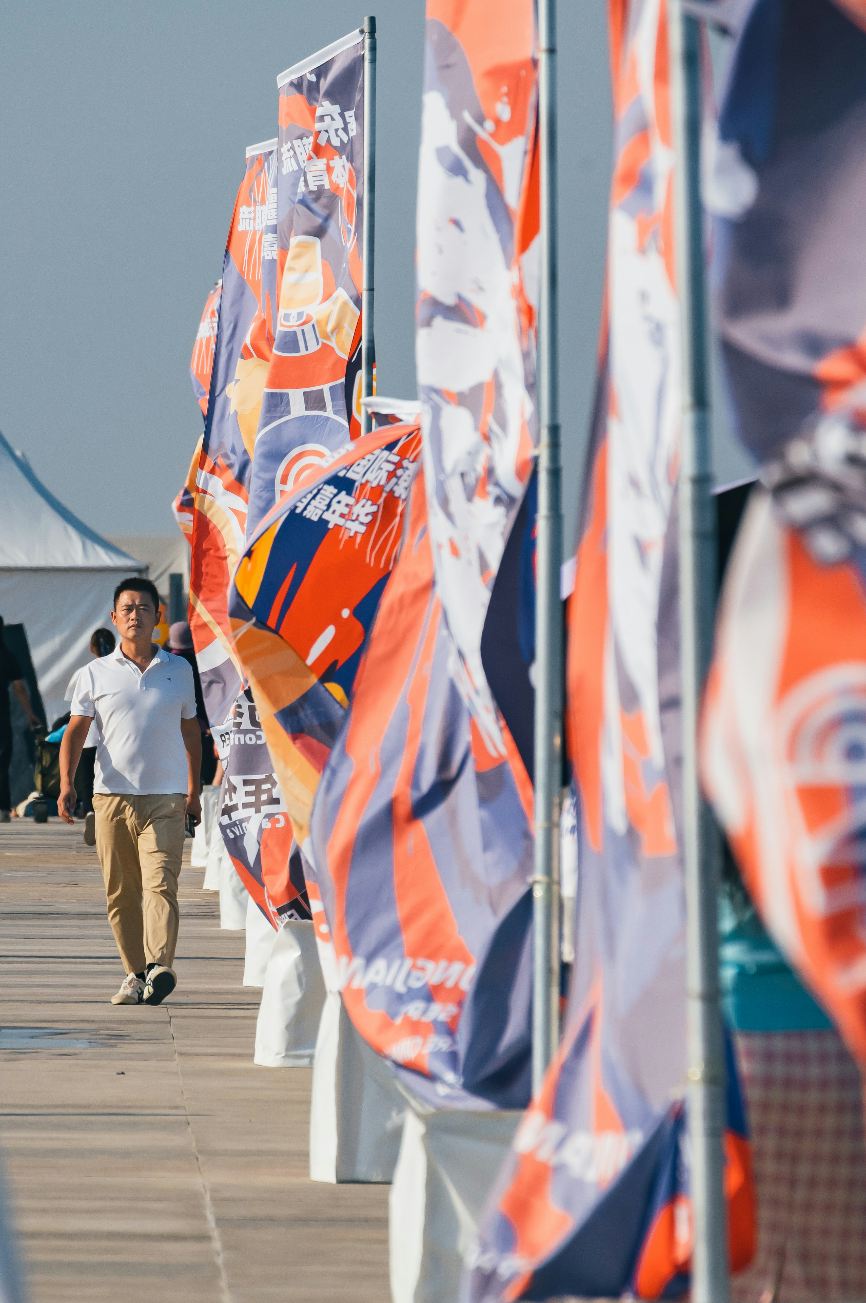 Man walks past colorful flags in an outdoor setting.