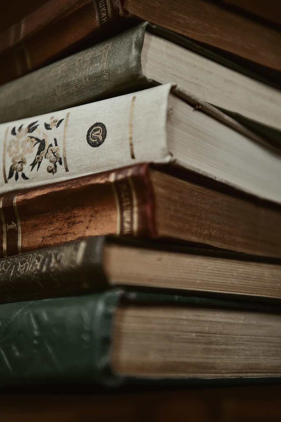 A close stack of antique leather-bound books with worn, gilded spines