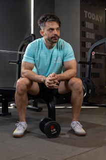 Man sits in a gym, contemplating his workout.