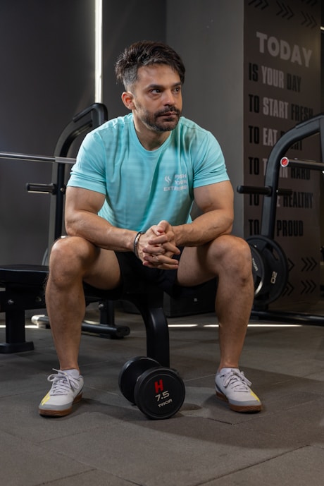 Man sits in a gym, contemplating his workout.