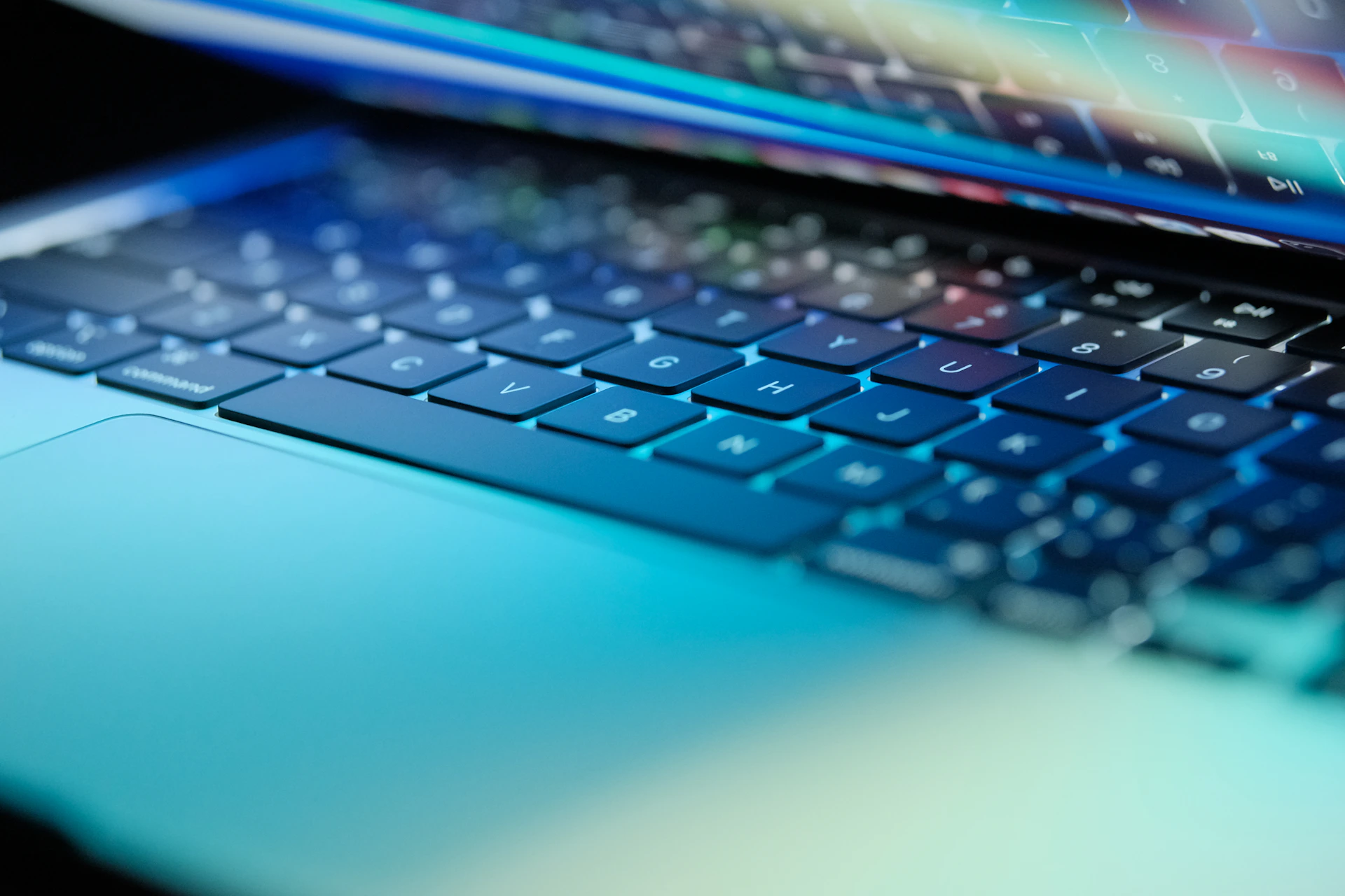 A laptop keyboard is lit up in blue