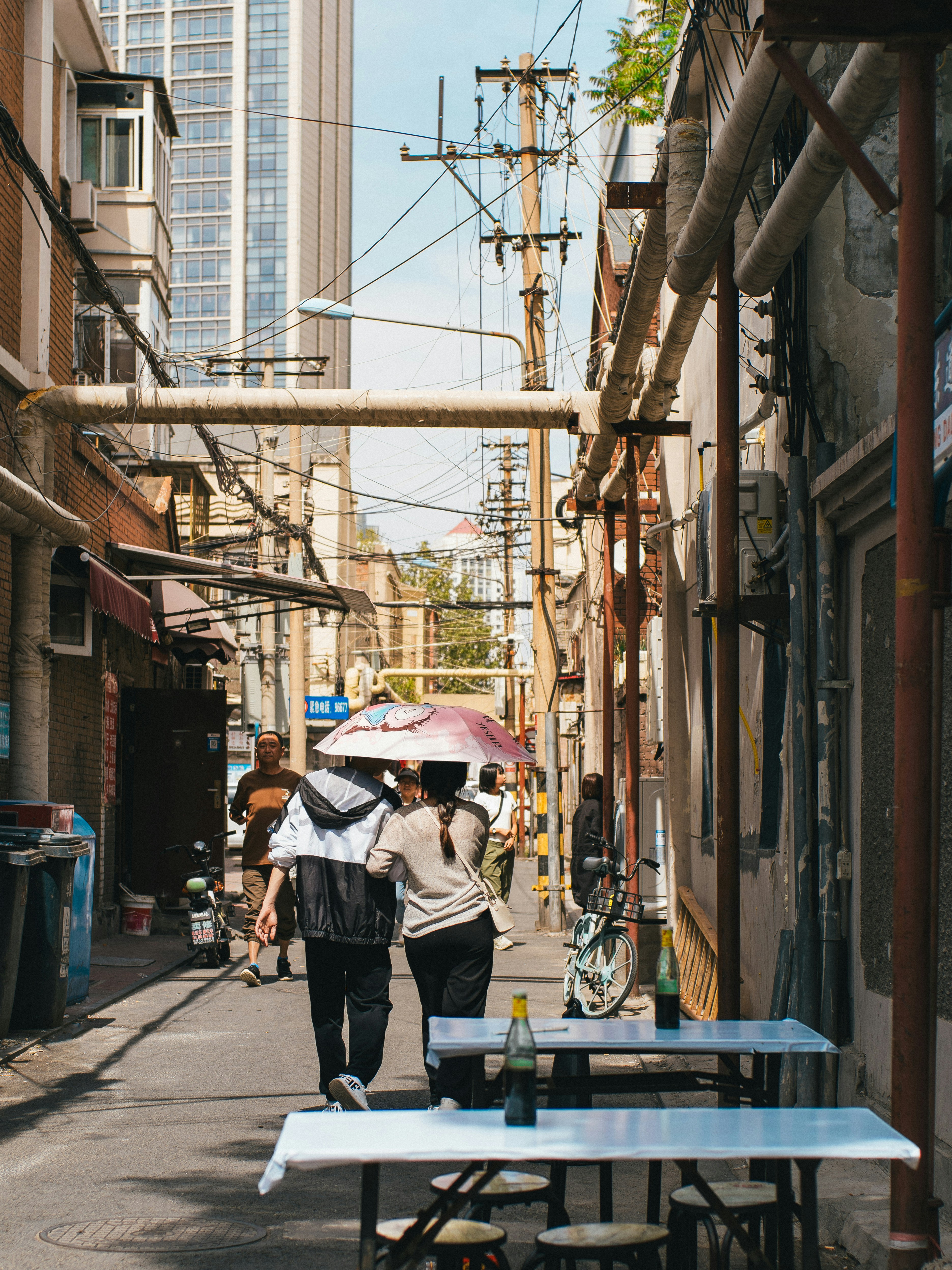 La gente camina por un callejón estrecho con cables aéreos.