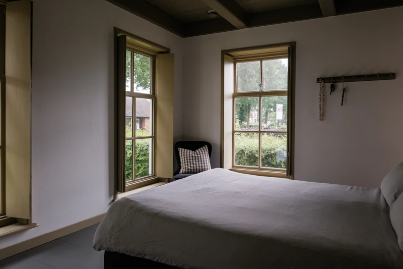 Camera con due finestre e letto accogliente