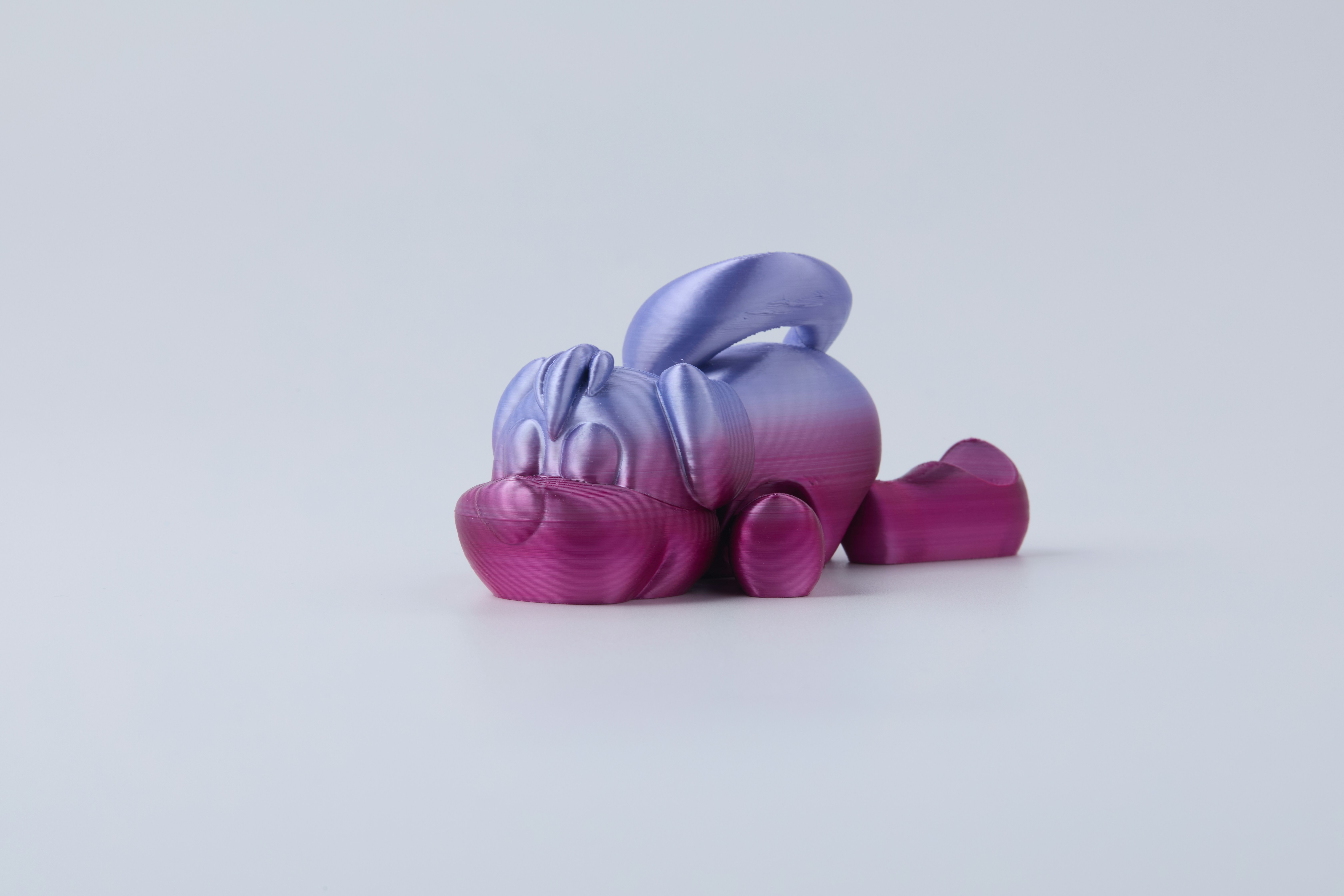 A playful 3D printed puppy in dreamy pink-purple gradient, showcasing filament color transitions and character design.