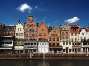Colorful buildings line a river under a blue sky.