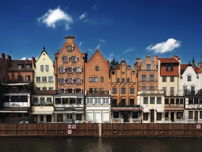 Colorful buildings line a river under a blue sky.