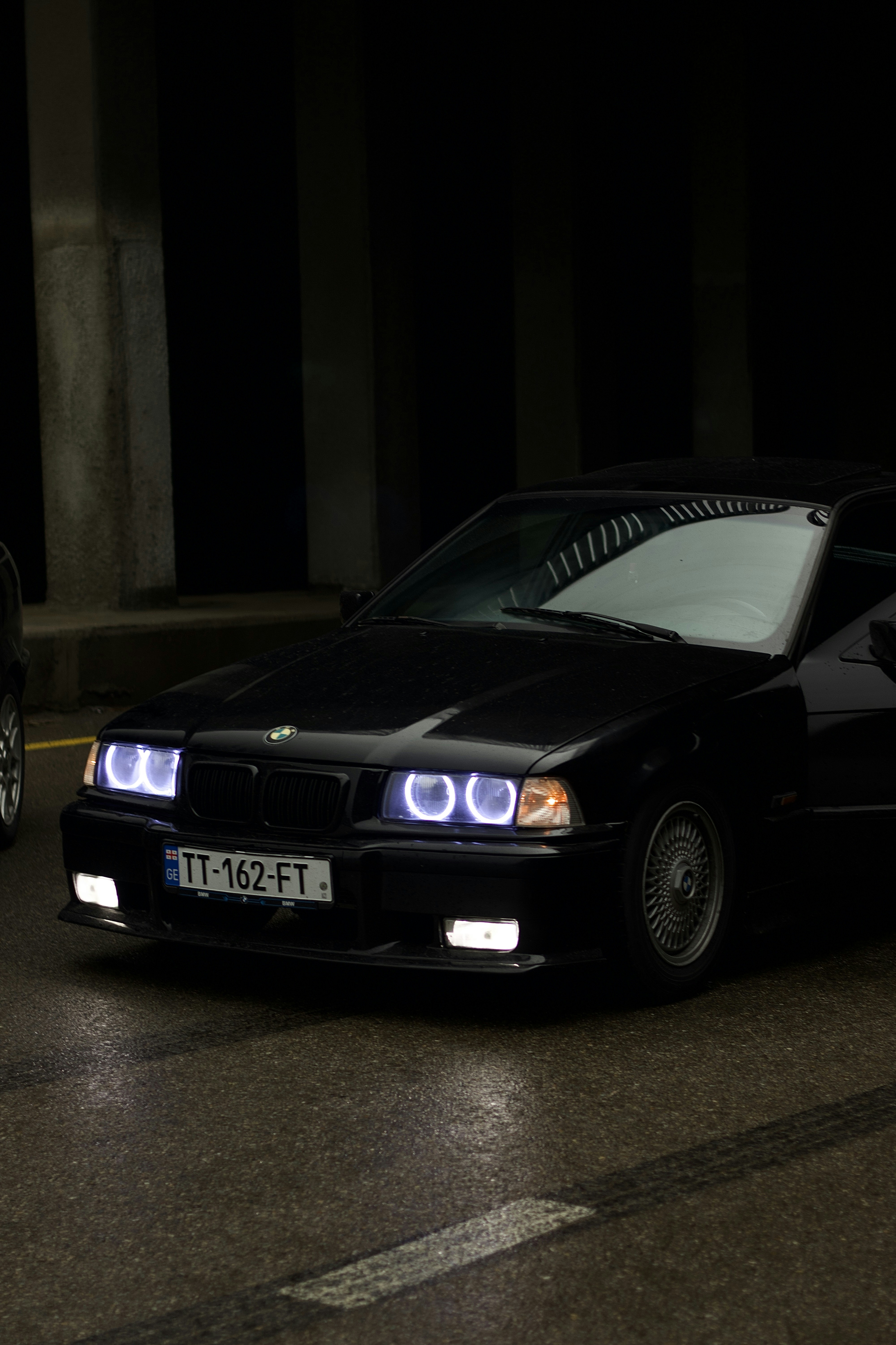 A black BMW car is parked in the dark.