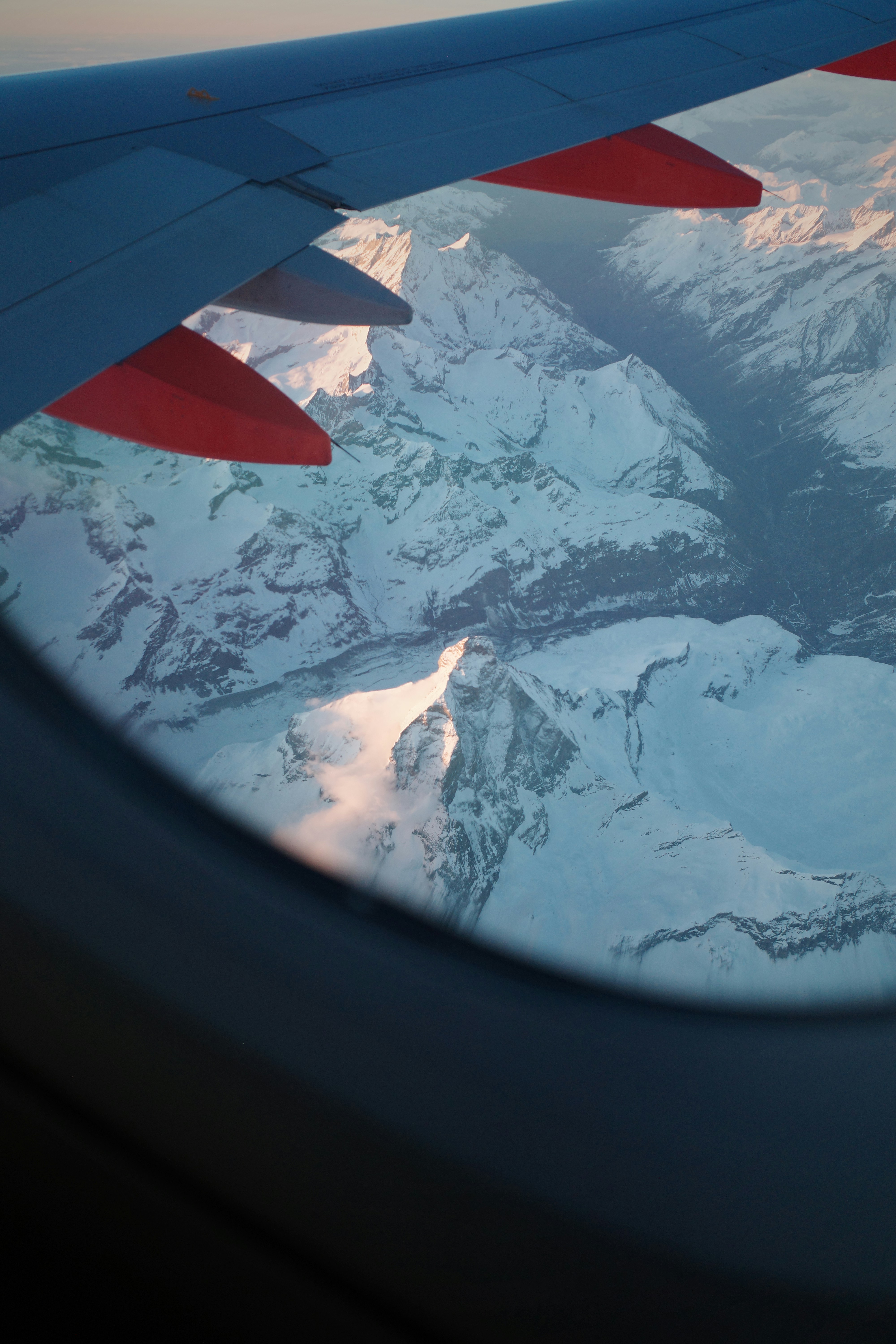 View of snowy mountains from an airplane window.