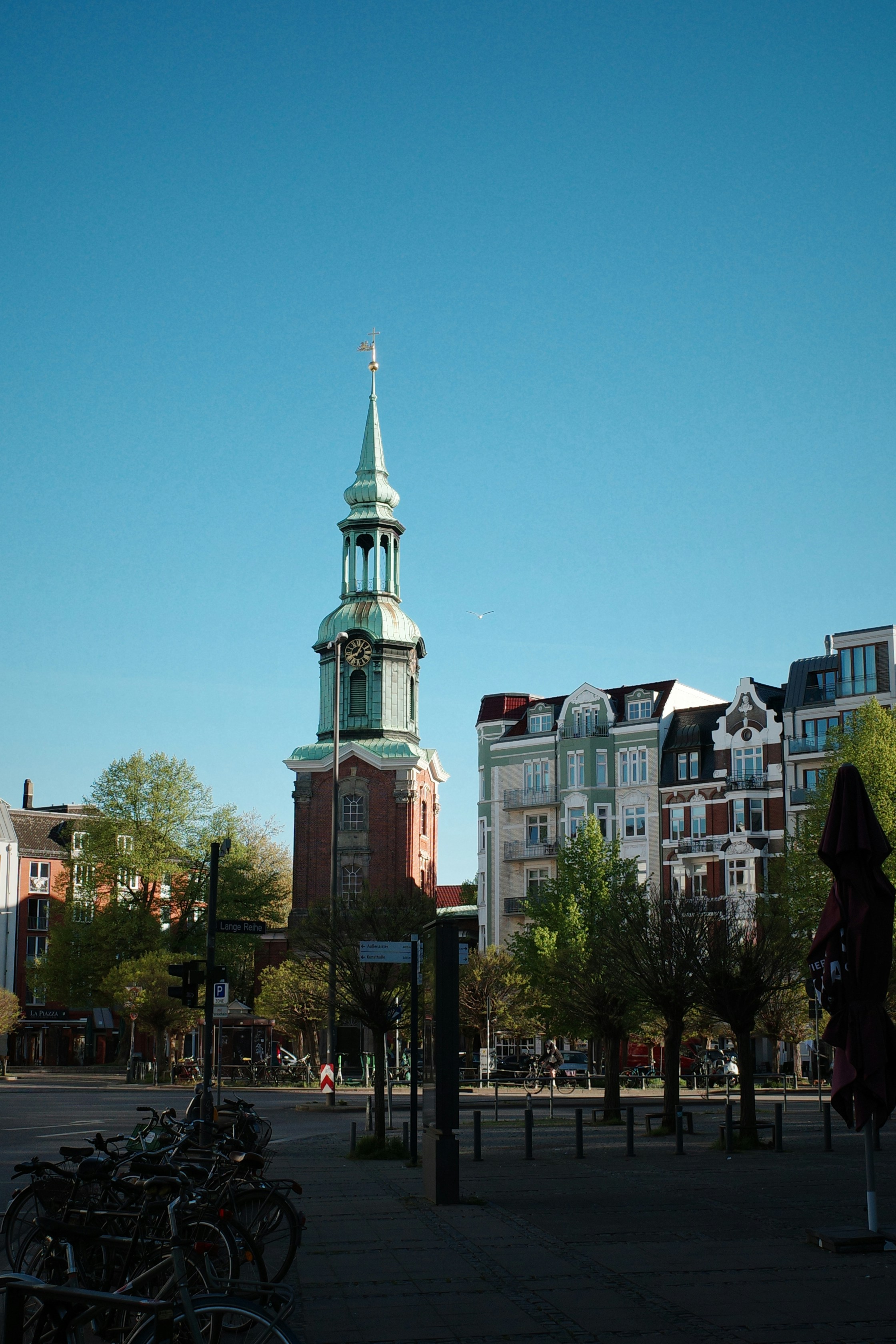 A church tower and buildings stand under a blue sky.