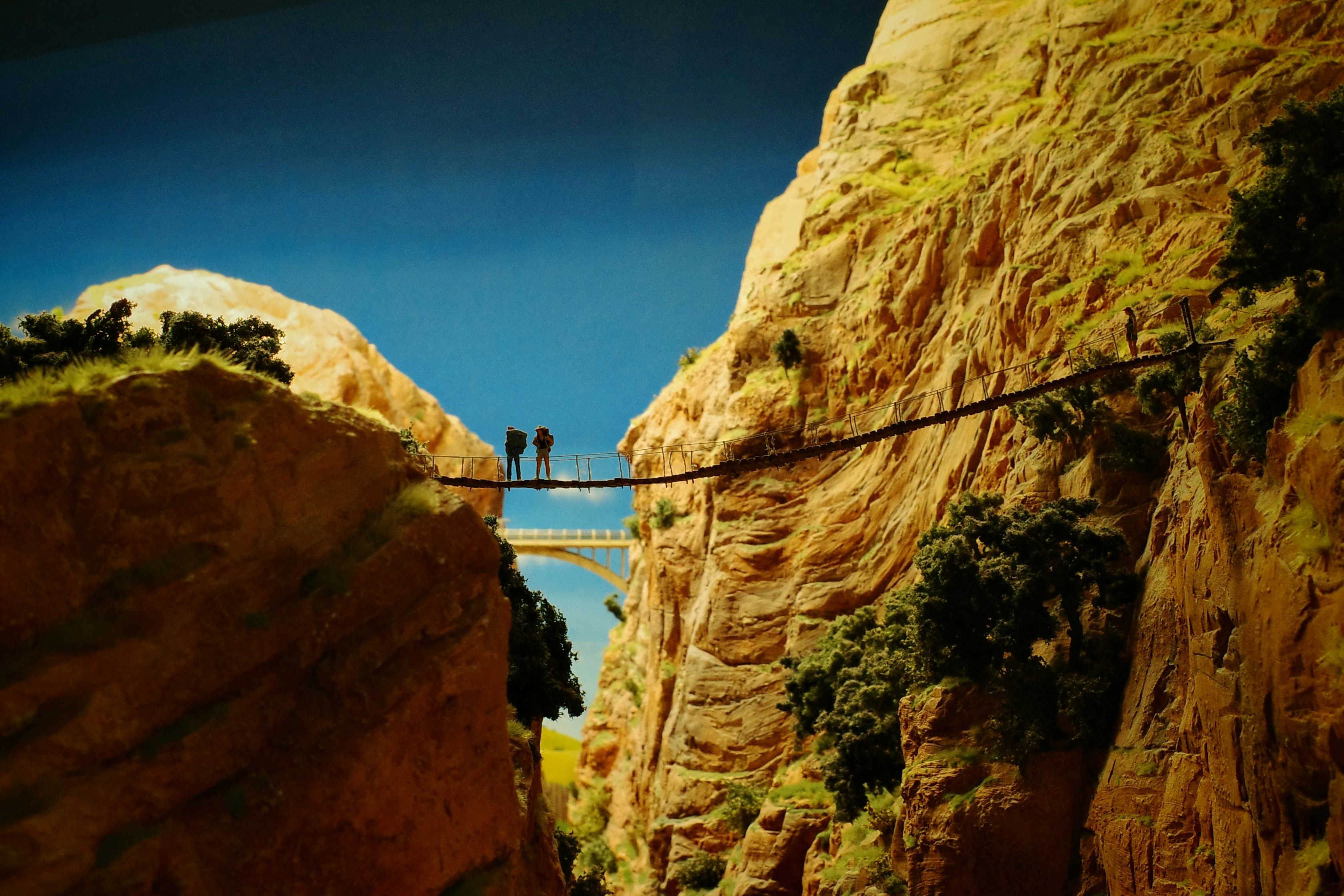 People cross a rope bridge over a canyon.