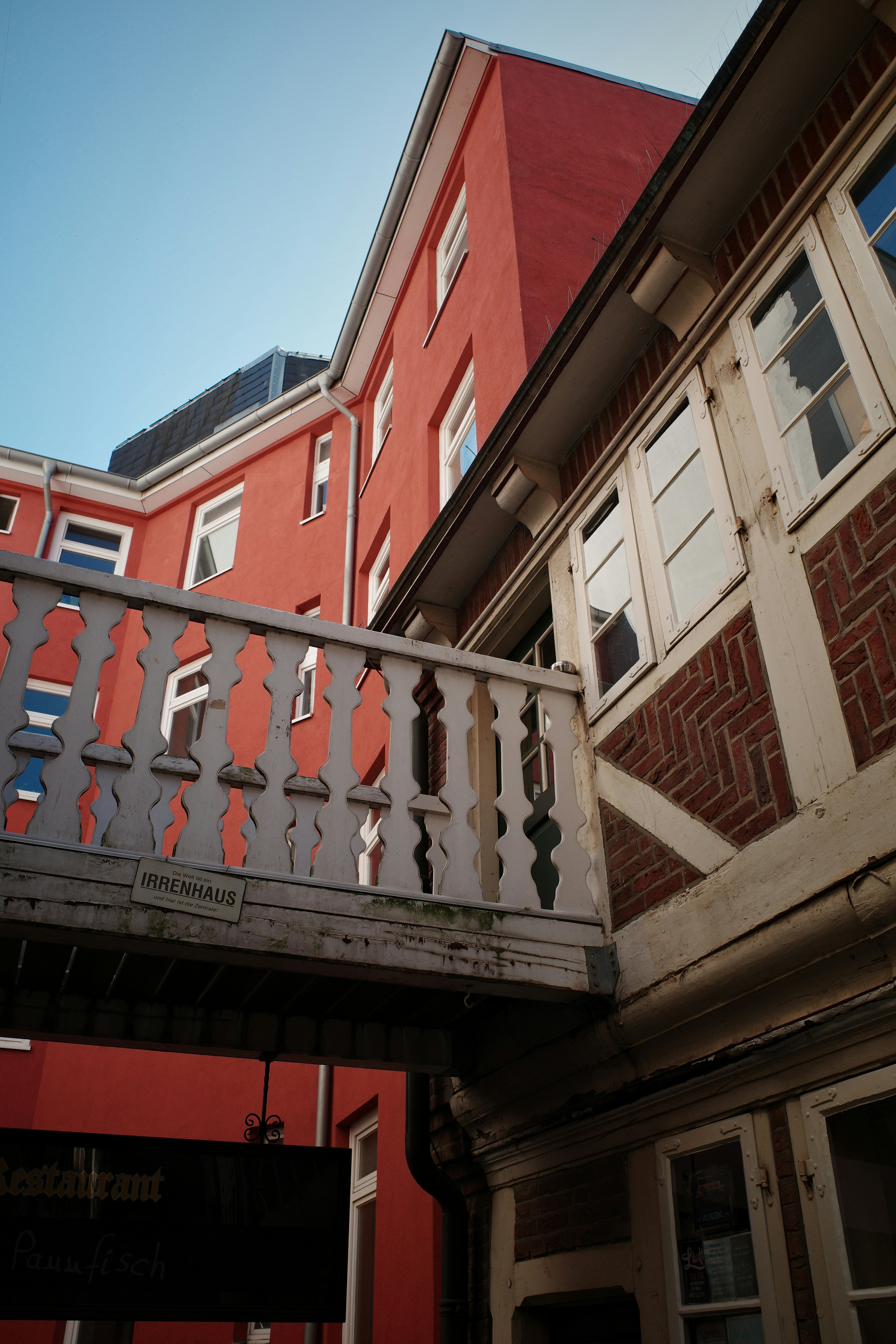 Buildings connected by a bridge against a blue sky.