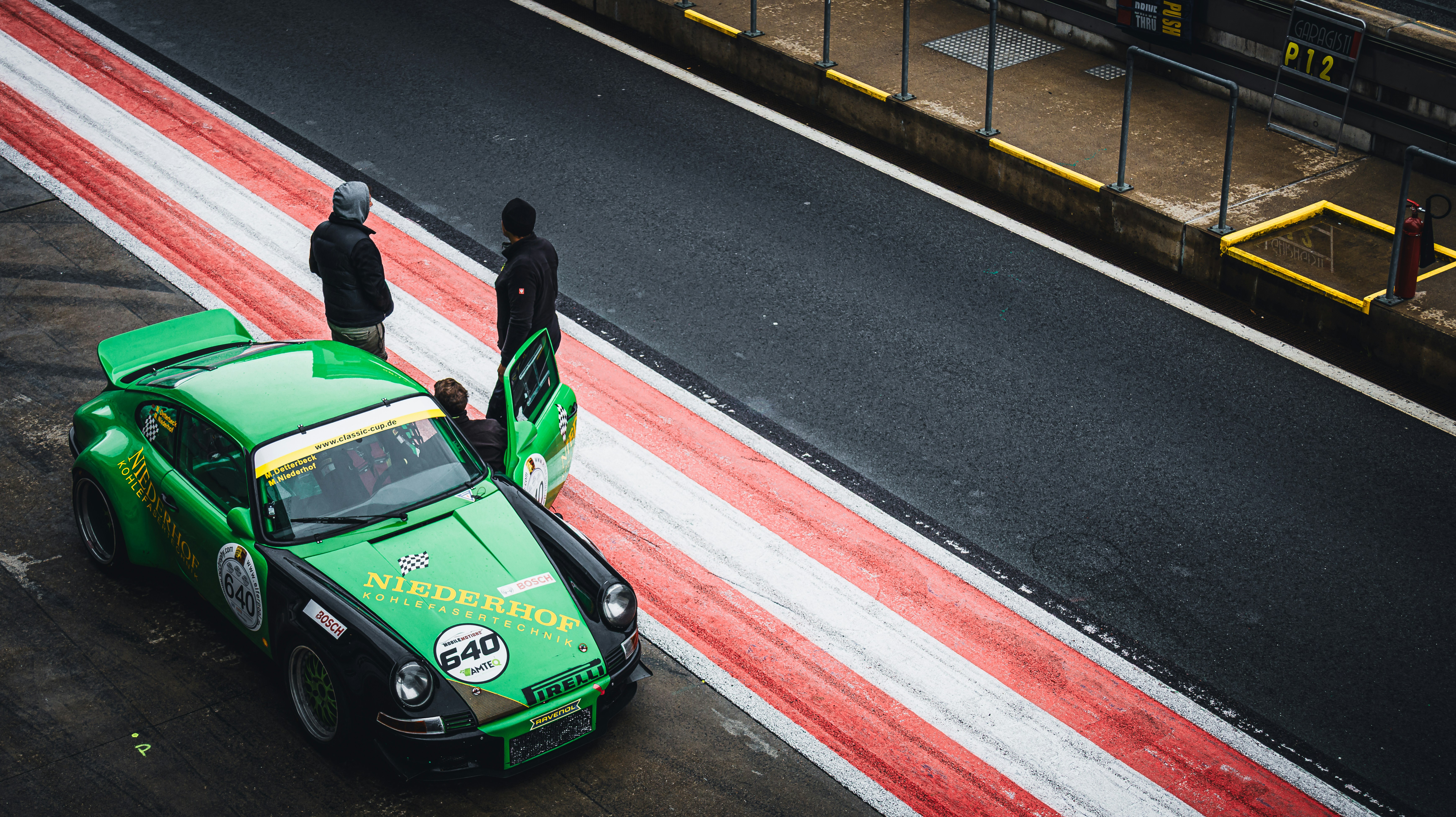 Two people standing next to a race car.