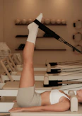 Woman does pilates exercise on a reformer machine.