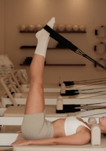 Woman does pilates exercise on a reformer machine.