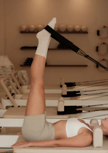 Woman does pilates exercise on a reformer machine.