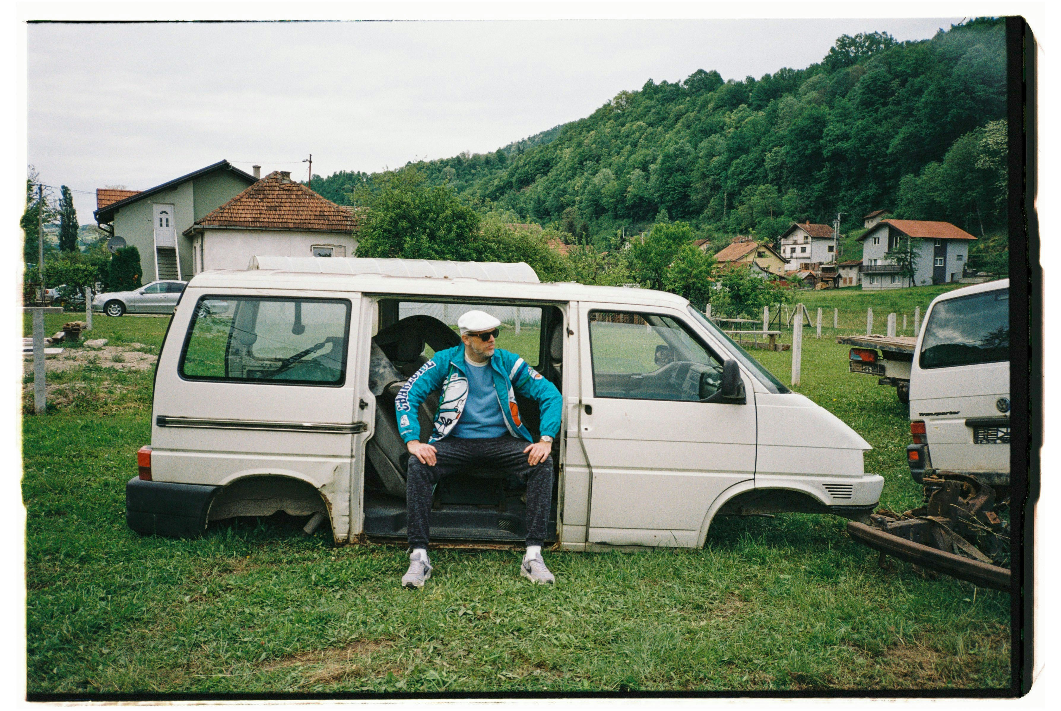 A man sits in a van without its wheels.