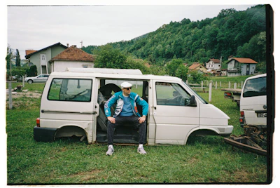 A man sits in a van without its wheels.