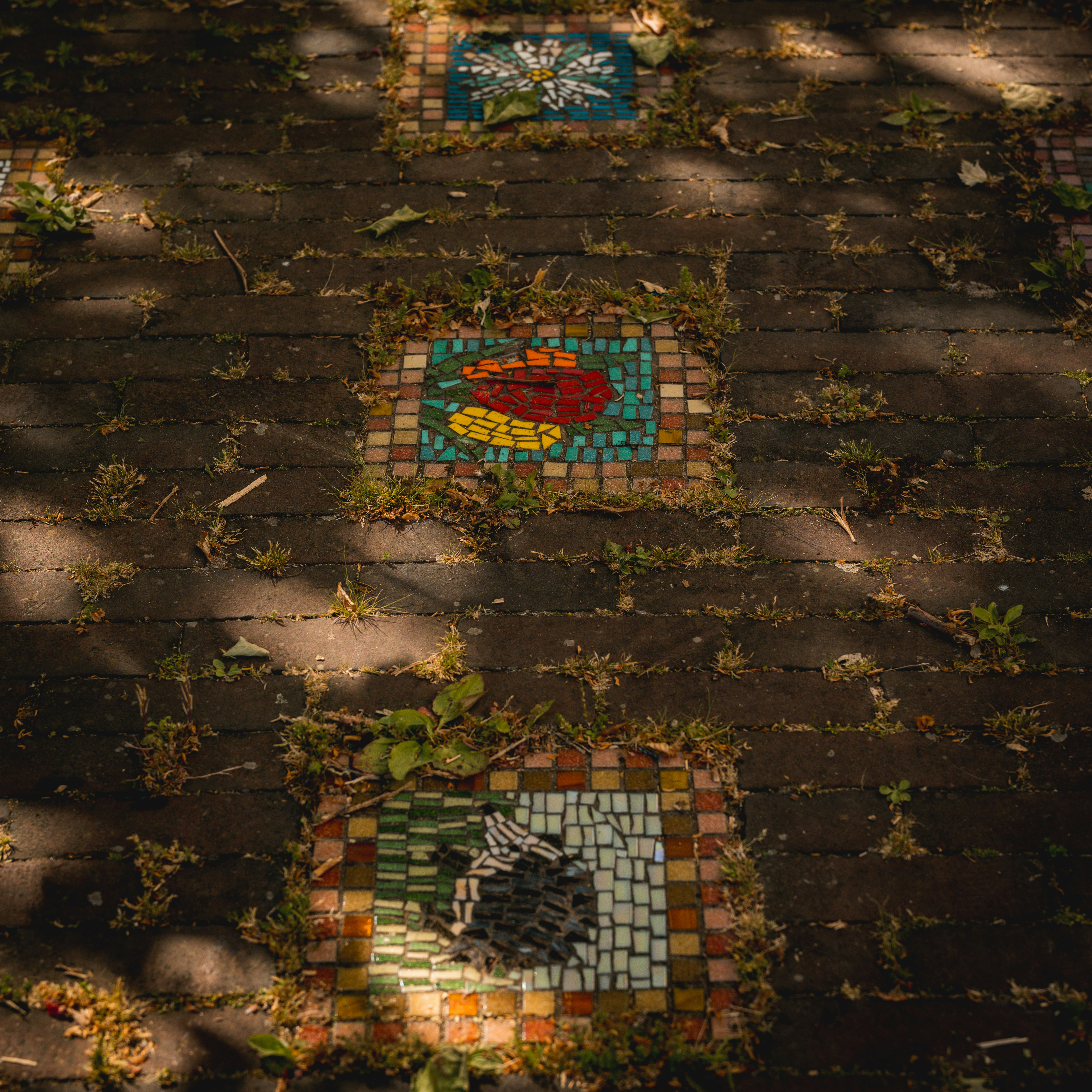 Colorful mosaic tiles decorate a brick path.