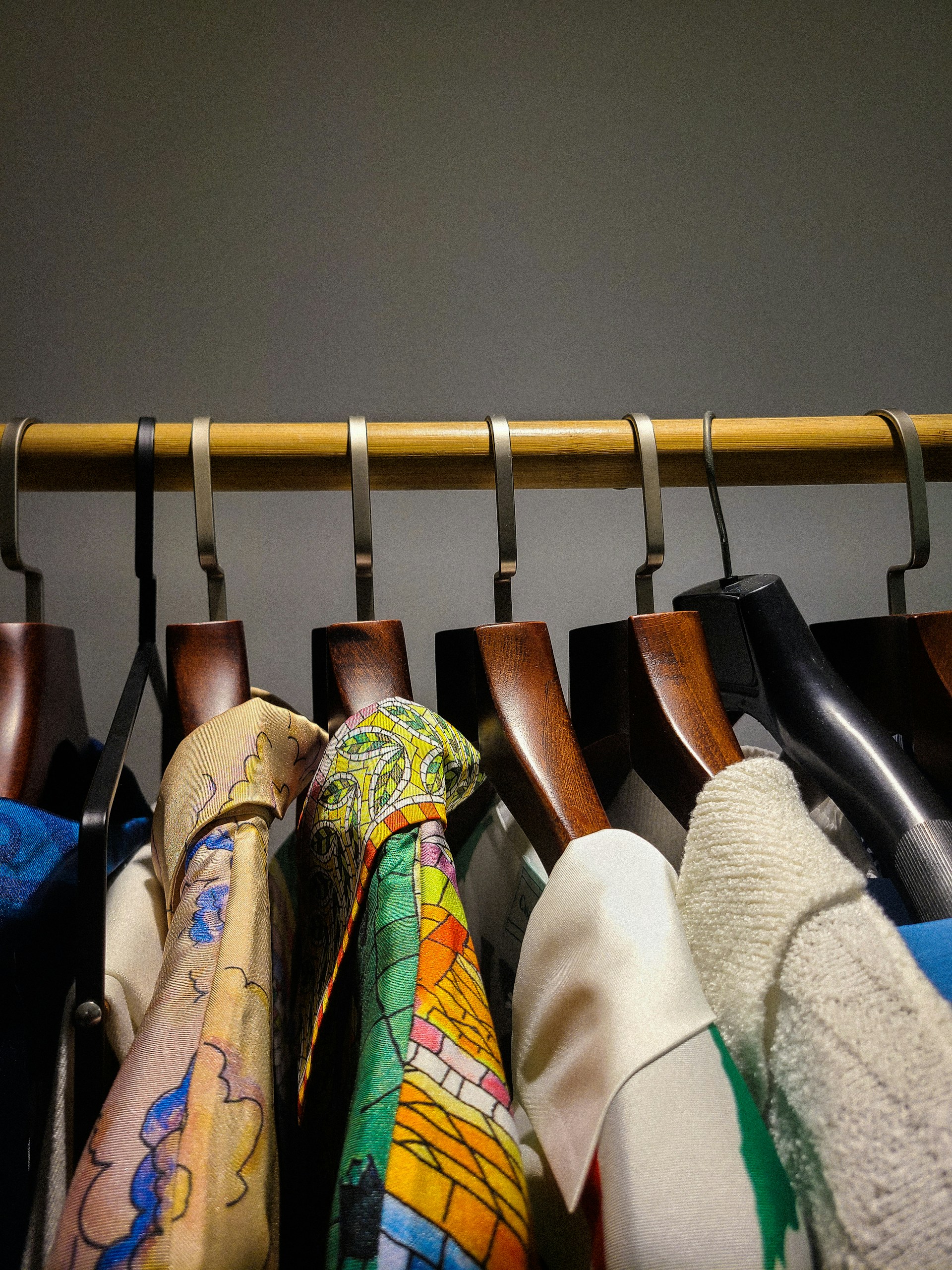 Clothes hang neatly on a wooden rail.
