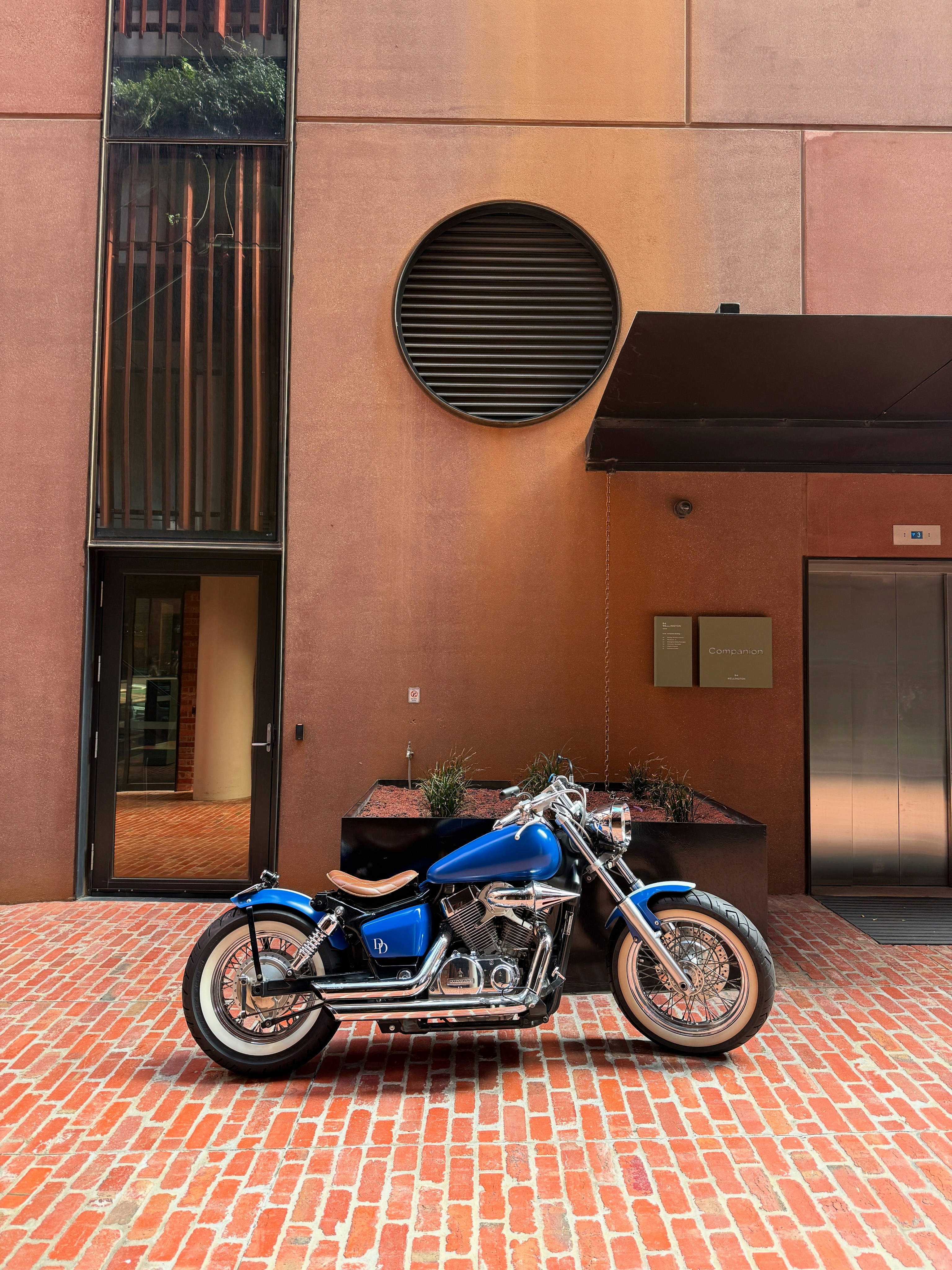 A blue motorcycle stands in front of a building.