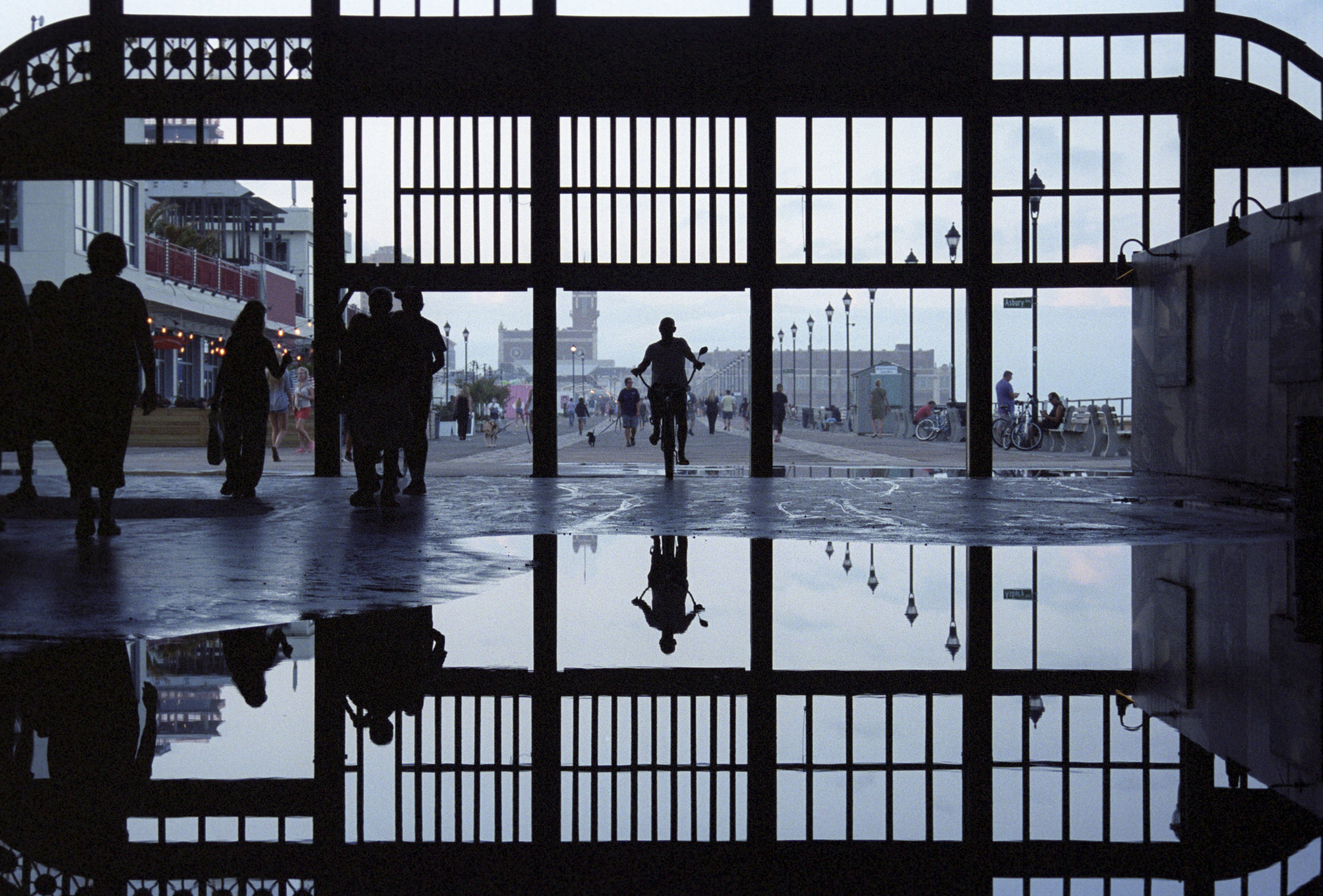 A cyclist rides by the beach's reflective puddles.