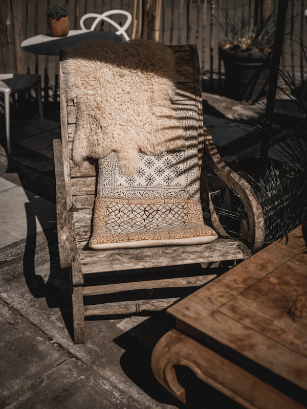 Wooden lounge chair with a soft blanket in the sun