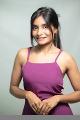A young woman poses in a purple dress.