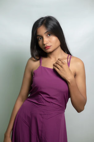 A woman poses in a purple dress.