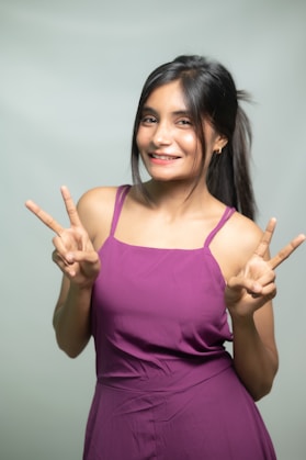 A cheerful woman gives the peace sign.