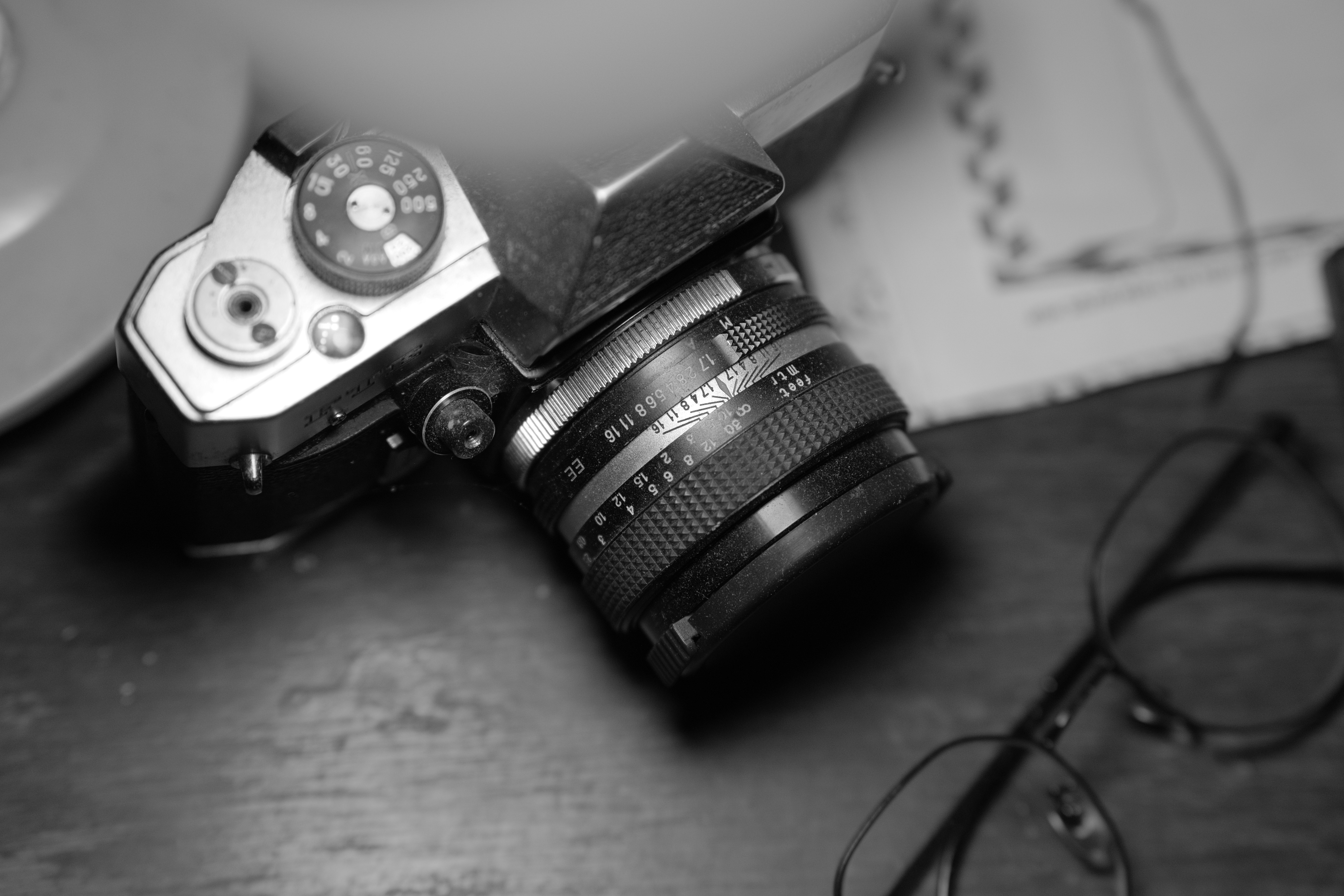An old film camera and glasses sit on a table.