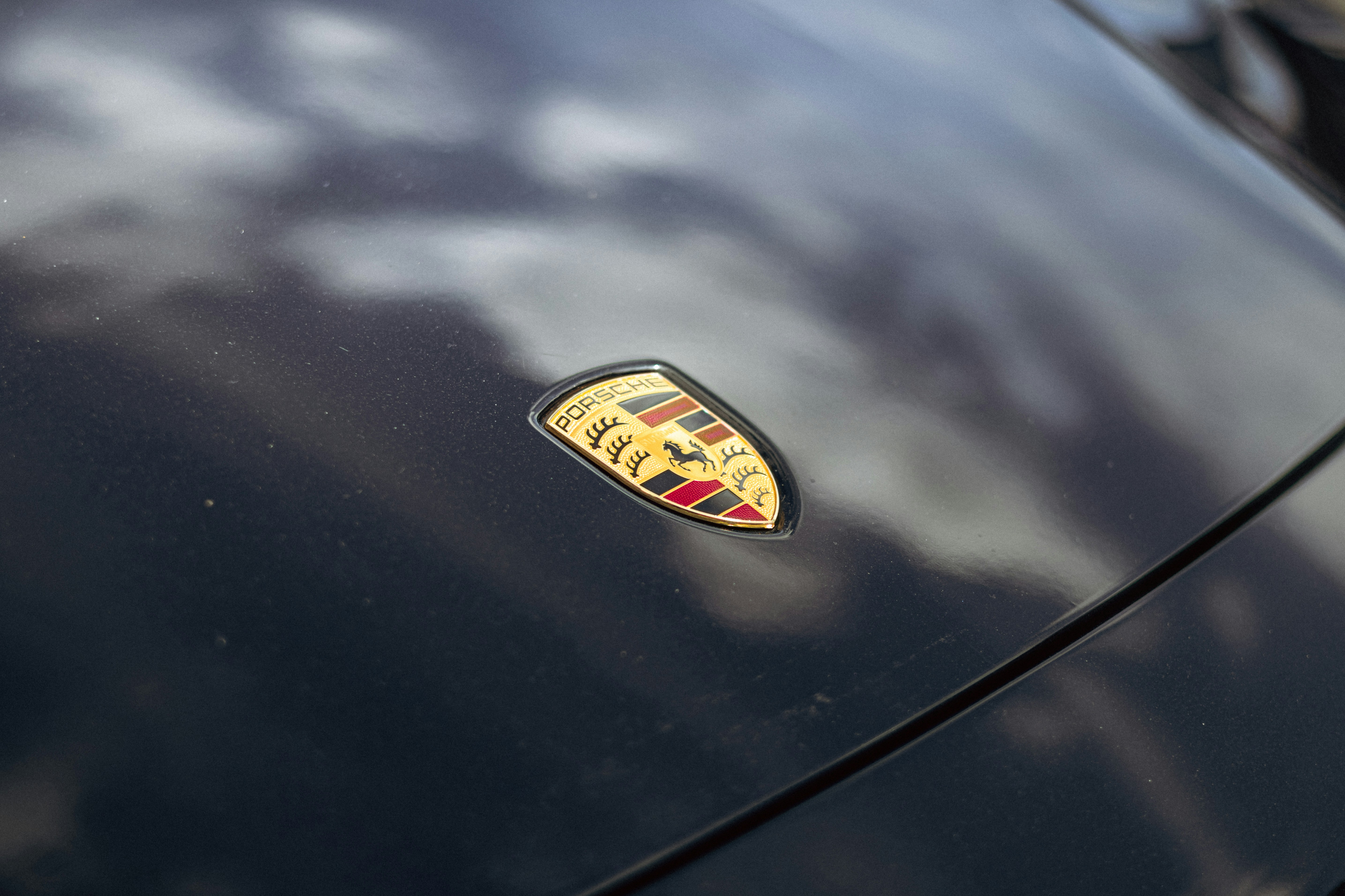 A porsche logo is seen on a car's hood.